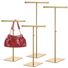 three gold and red handbags are on display in front of the same bag holder