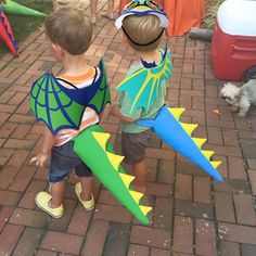 two young boys standing next to each other on a brick walkway holding kites in their hands