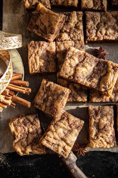 cinnamon sugar brownies cut into squares and placed on a plate next to an assortment of cinnamon sticks