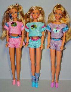 three barbie dolls standing next to each other in front of a white wall and wearing matching outfits