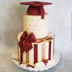 a three tiered cake decorated with red and white stripes, bows and a graduation cap