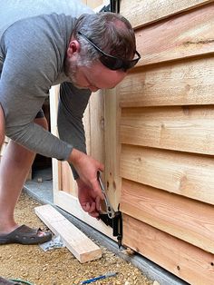 a man is working on the side of a house with wood planks and plywood