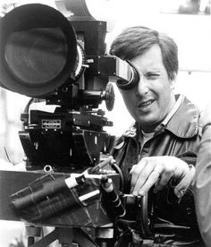 black and white photograph of a man holding a camera in front of a video camera