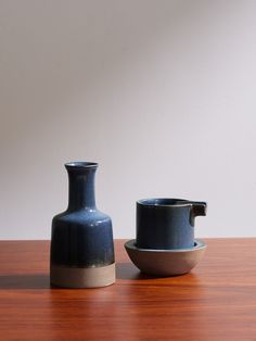 two black vases sitting on top of a wooden table