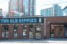 two old hippies sign on the side of a building in front of tall buildings