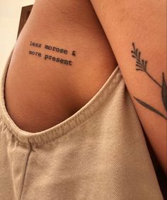 the back of a woman's shoulder with an inscription on it that reads less morse and more present