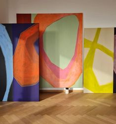 four abstract paintings are on display in an empty room with hard wood floors and parquet flooring