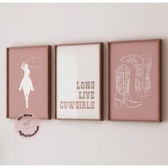 three framed art pieces hang on the wall above a pink vase and two white cowboy boots