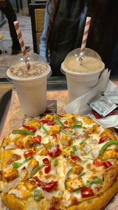 a pizza sitting on top of a table next to two drinks