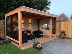 a backyard with a wooden shed and black furniture on the patio, surrounded by green grass