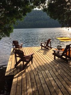 two lawn chairs sitting on top of a wooden dock