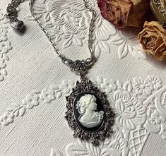 Lady Cameo Necklace! This beautiful "black and white" cameo necklace is romantic and whimsical! The cameo is very detailed and intricate and is set in a very ornate antique silver pendant....and attached to an antique silver bale and chain.... I have added a tiny vintage silver heart charm to the back of the clasp! The perfect Christmas gift for her!! Perfect gift for that special someone in your life! Please select if you would like this item gift wrapped....I will also include a card with your special message! Thank you for taking time to browse my shop "Veronica Rose Designs"... https://www.etsy.com/shop/veronicarosedesigns?ref=seller-platform-mcnav White Cameo Necklace For Gift, Gothic Cameo Necklaces For Gifts, Luxury Silver Cameo Necklace, Silver Gothic Cameo Jewelry, Victorian Cameo Silver Necklace, Silhouette Necklace, Cameo Necklace, Rose Design, Christmas Gifts For Her