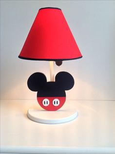 a lamp with a mickey mouse face on it and a red shade over the base