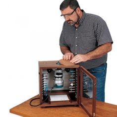 a man working on an electrical device in a wooden box with wires attached to it