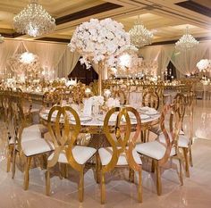 an elaborately decorated banquet hall with chandeliers and white flowers on the tables