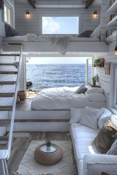 a loft bed with stairs leading up to the top floor and an ocean view in the background