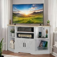 a flat screen tv sitting on top of a white entertainment center next to a window