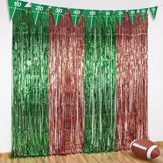 a football is sitting on the floor in front of a curtain with streamers that are green and red