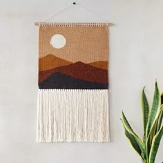 a wall hanging with a mountain scene on it and a potted plant next to it