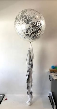 a balloon with confetti and streamers hanging from it's side on a table