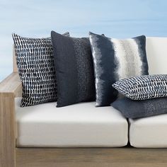 a white couch with black and white pillows on it's back cushions are lined up against each other