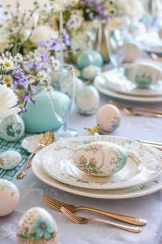 an easter table setting with blue and white eggs on plates, silverware, and floral centerpieces