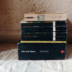 four books stacked on top of each other in front of a white sheet covered wall