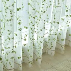 white curtains with green flowers on them in front of a window