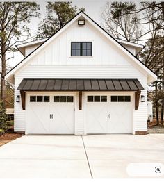 a white house with two garage doors and windows