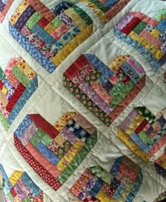 a close up of a colorful quilt on a cell phone screen with the caption, log cabin hearts quilt