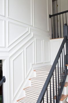 a staircase with white walls and black railing