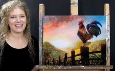 a woman standing next to two paintings of roosters on easel stands in front of a fence