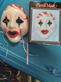 a pair of clown masks sitting on top of a blue table next to a box