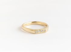 a yellow gold ring with three diamonds on the side, set against a white background