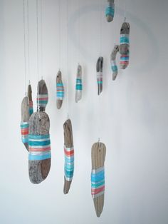 an assortment of wooden shoes hanging from strings on a white wall with blue and red stripes