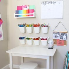 a white table topped with lots of cups filled with crayons