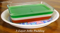 three layer jello pudding in a white bowl on a wooden table with colorful napkins