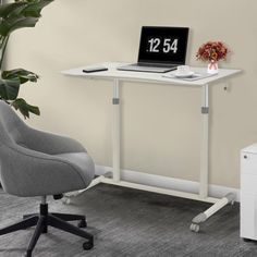 a desk with a laptop on it next to a white chair and potted plant