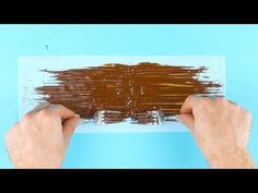 two hands are holding paint over a piece of paper