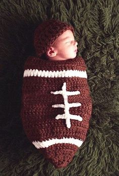 a baby is sleeping in a crocheted football blanket