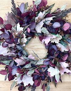 a wreath with purple and white flowers on a wooden surface