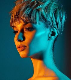 a woman with short hair is posing for a photo in front of a blue background