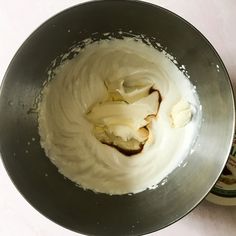 a metal bowl filled with whipped cream next to a bottle