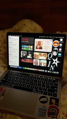 an open laptop computer sitting on top of a bed covered in sheets and pillows,