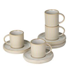 four white cups and saucers sitting on top of each other in front of a white background