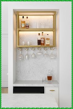 the shelves are filled with bottles and glasses on top of marble counter tops in this kitchen