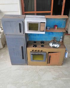 a toy kitchen made out of cardboard with a sink and stove top oven in the middle