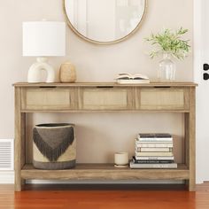 a table with books, vases and a round mirror on the wall above it