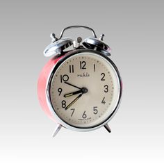 an alarm clock with two bells on each side and one bell at the top, in front of a gray background