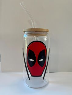 a glass jar with a deadpool face on it and a straw in the lid